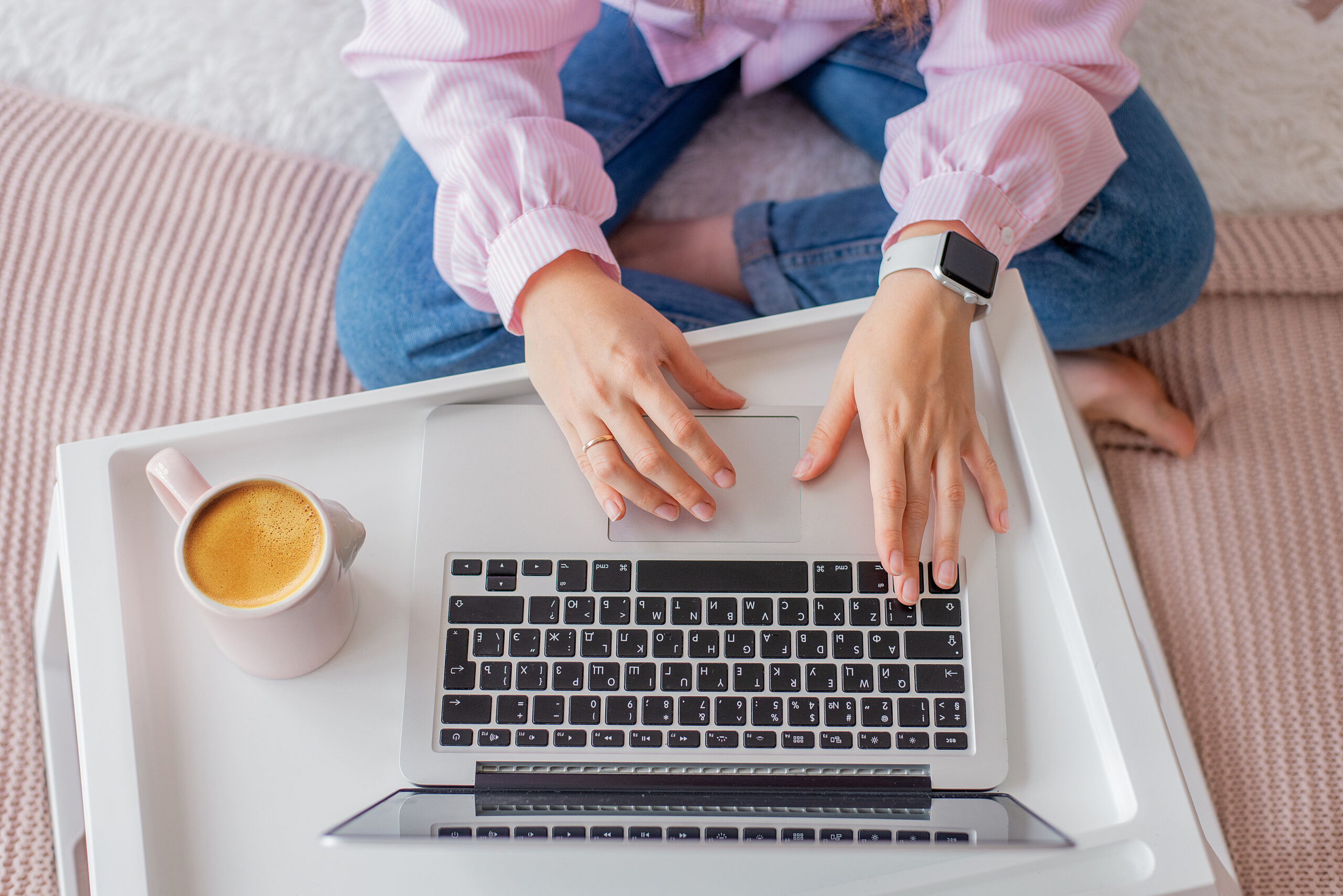 Female workspace with female hands, laptop, pink peonies bouquet. Top view feminine background. Flat lay women's office desk.